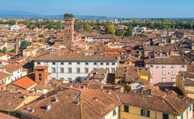 Historic towers and terracotta roofs in Lucca Italy cityscape with greenery in the background