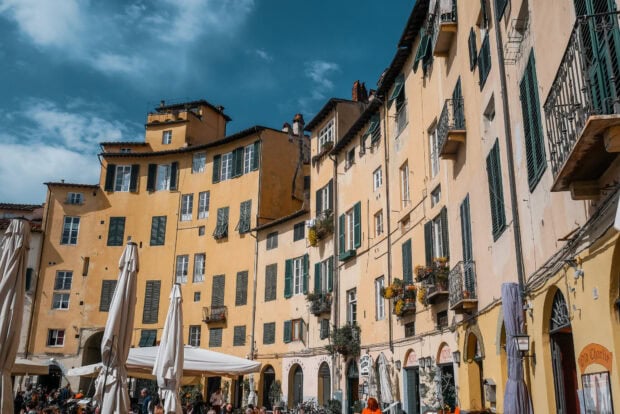 Old buildings and cafe terraces in Lucca Italy on a sunny day with blue sky