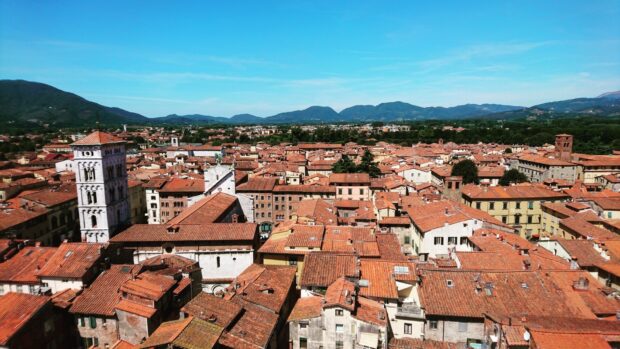 A panoramic view of Lucca Italy showing historic buildings and rooftops under a blue sky