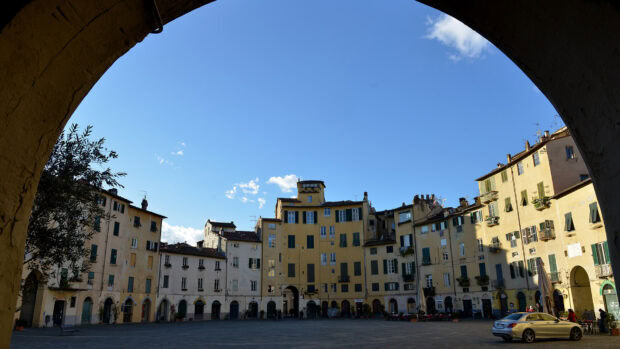 Historic buildings of Lucca Italy under a clear blue sky viewed through an archway