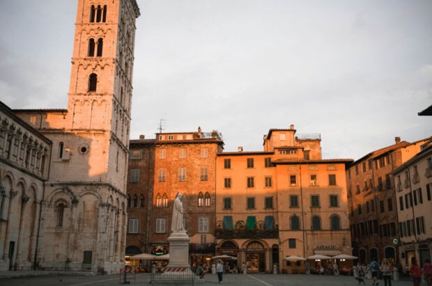 Historic square in Lucca Italy with old buildings and statue at sunset