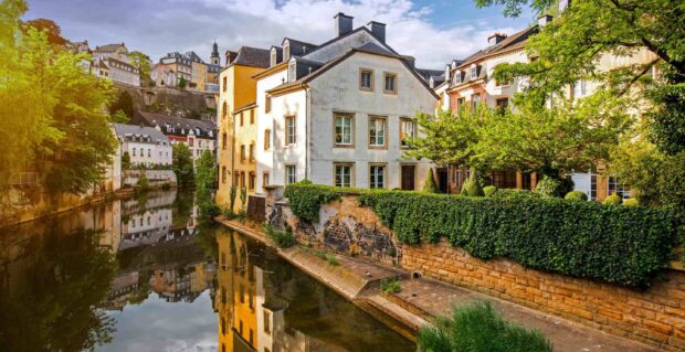 Beautiful riverside architecture in Luxembourg with lush greenery and clear reflections in water