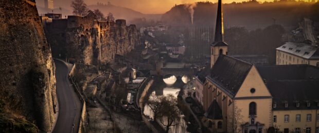Ancient Luxembourg fortifications and historic buildings at sunset with peaceful river view