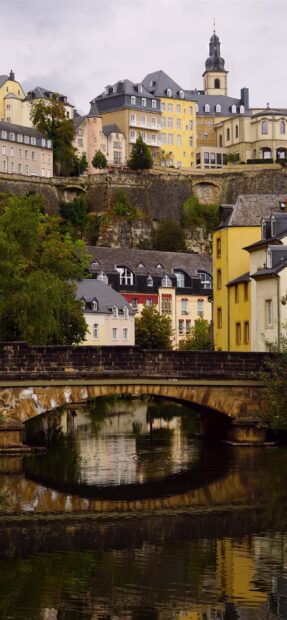 Historic Luxembourg buildings with river and stone bridge reflecting in water