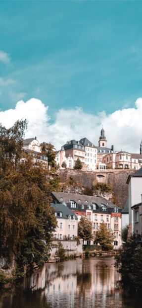 Scenic view of Luxembourg city with river and historic buildings under blue sky