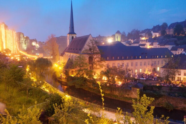 Night view of Luxembourg cityscape with illuminated church and riverside greenery