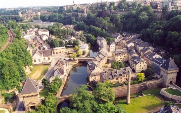 A scenic view of Luxembourg city with historic architecture and lush greenery surrounding the river