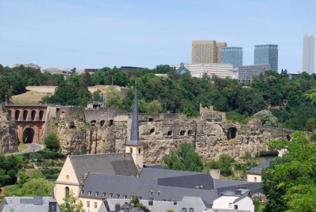 Historic architecture and modern buildings in Luxembourg cityscape with green trees and blue sky