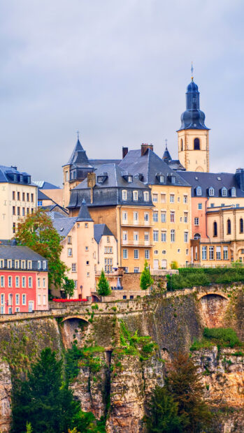 Historic architecture of Luxembourg city perched on cliffs with greenery around