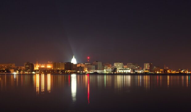 Nighttime cityscape of Madison Wisconsin reflecting on the calm lake with illuminated buildings