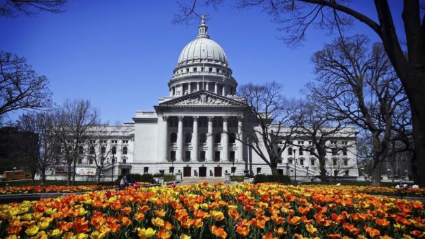 The Madison Wisconsin Capitol building with vibrant orange and yellow tulips in spring