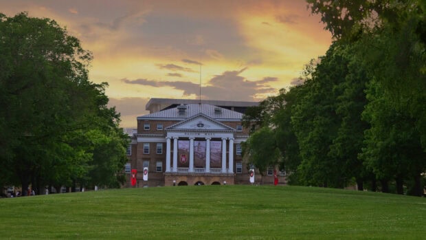 Bascom Hall is a famous landmark in Madison Wisconsin surrounded by green trees and open lawn during sunset