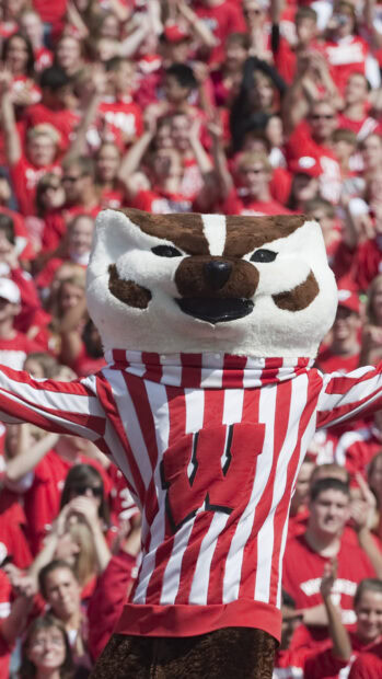 The Wisconsin badger mascot cheers in front of a lively crowd at a sports event