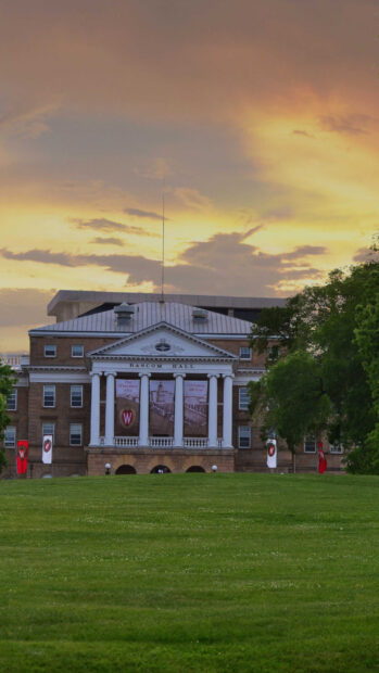 Bascom Hall in Madison Wisconsin stands prominently against a sunset sky with a lush green lawn in front