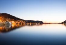 Boats docked along the calm waterfront in Mallorca during sunset with hills in the background