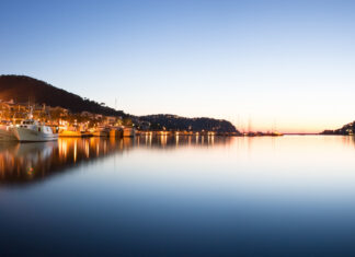 Boats docked along the calm waterfront in Mallorca during sunset with hills in the background