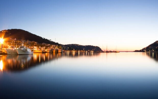 Boats docked along the calm waterfront in Mallorca during sunset with hills in the background