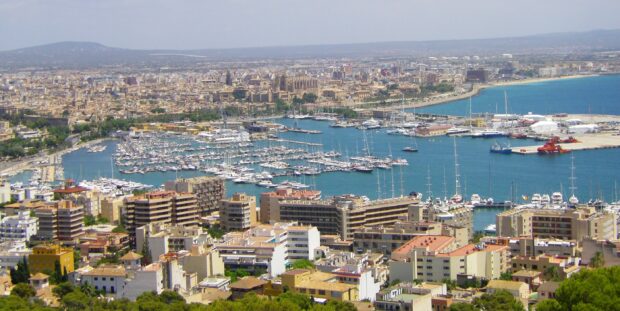 A panoramic view of Mallorca city with a marina full of boats and surrounding buildings