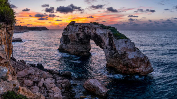Natural rock formation near Mallorca coastline during sunset with vibrant sky colors