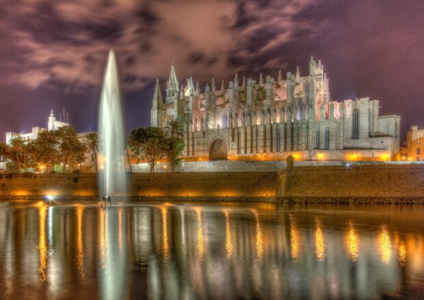 Historic cathedral architecture in Mallorca with illuminated fountain and reflections at night