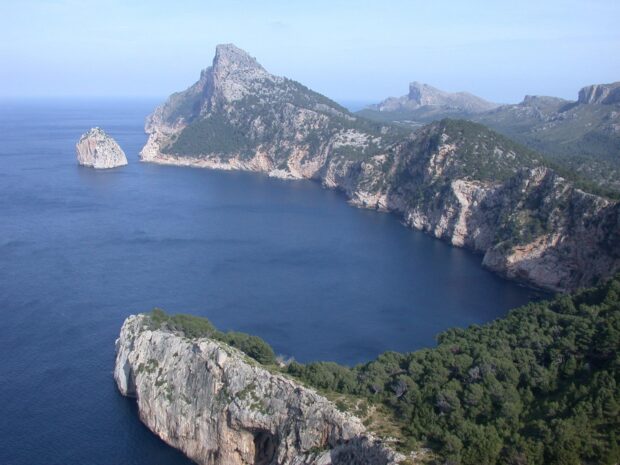 Rocky coastline and lush greenery of Mallorca coast with clear blue water