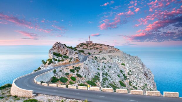 Winding road leading to a lighthouse on a rocky coast of Mallorca at sunset