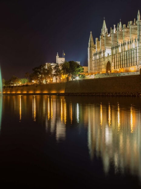Gothic architecture in Mallorca reflected in calm water at night