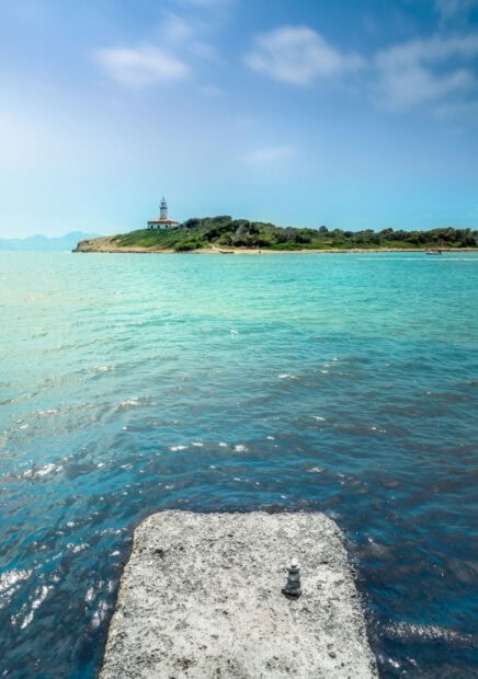A peaceful view of Mallorca with clear blue sea and a distant lighthouse on the coast