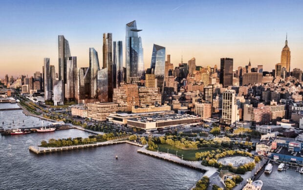 A stunning Manhattan cityscape with modern skyscrapers and waterfront parkland at sunset