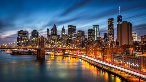 Nighttime view of Manhattan cityscape with Brooklyn Bridge and illuminated buildings on water