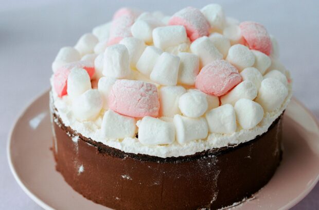 A delicious chocolate cake topped with white and pink marshmallow pieces on a plate