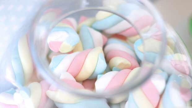 Colorful striped marshmallow candies in a clear jar viewed from above