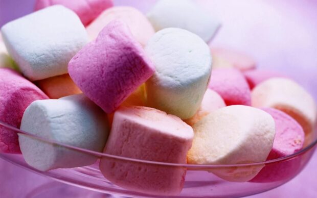 Colorful marshmallow pieces piled in a glass bowl with soft lighting
