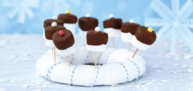 Marshmallow treats dipped in chocolate with colorful sprinkles on a white ring display