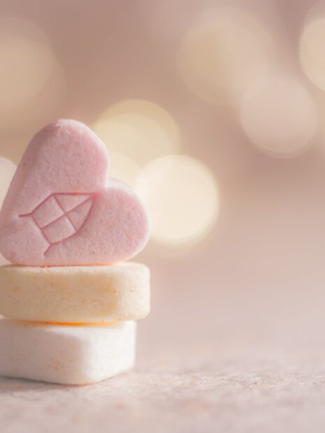 Pink heart shaped marshmallow stacked on soft pastel sweets with bokeh background