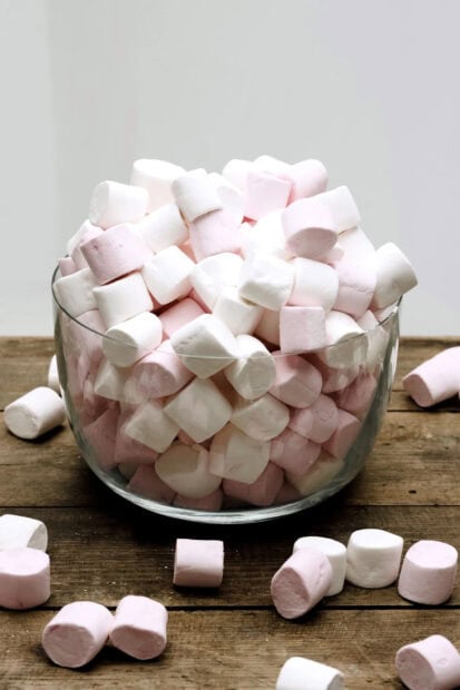 A bowl filled with colorful marshmallow piled high on a wooden surface