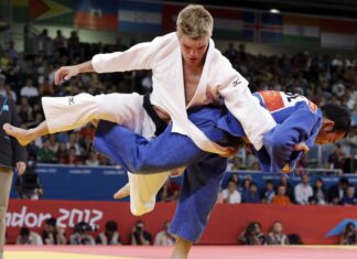 Male athlete executing judo throw during martial art competition in front of audience