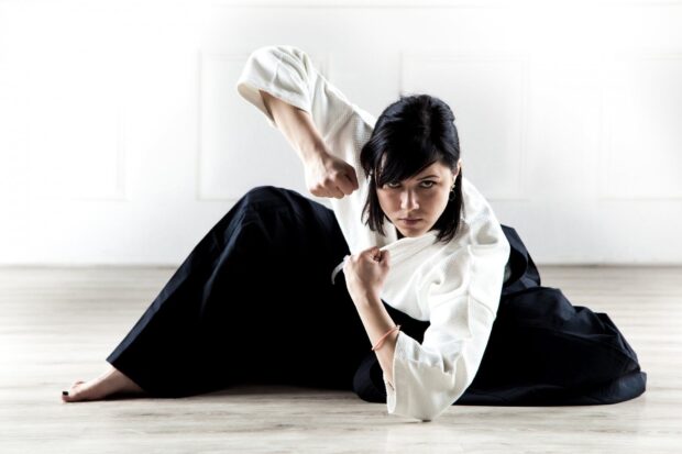 Woman practicing martial art in traditional uniform performing a low fighting stance