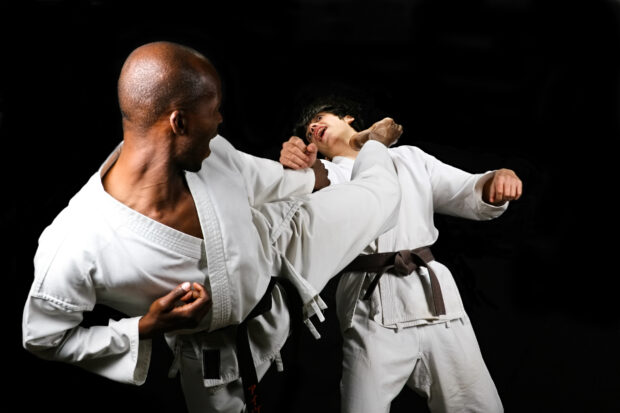 Two martial artists sparring in a dojo wearing traditional uniforms