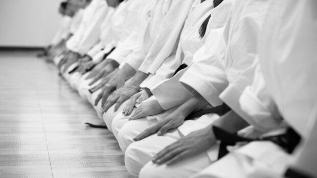A group of martial art practitioners sitting in a row in traditional uniforms