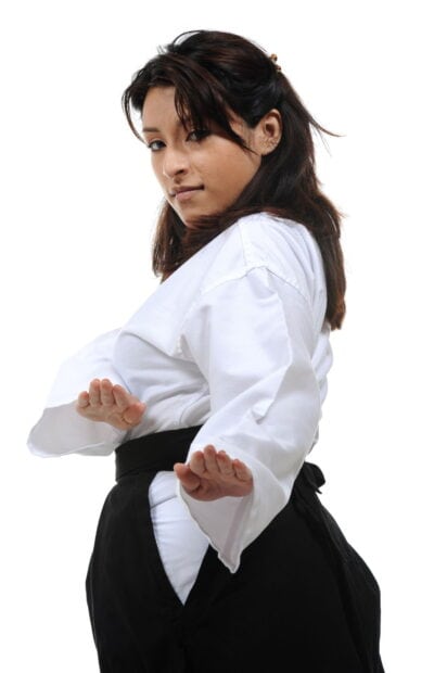 Woman practicing martial art pose wearing traditional uniform with black belt
