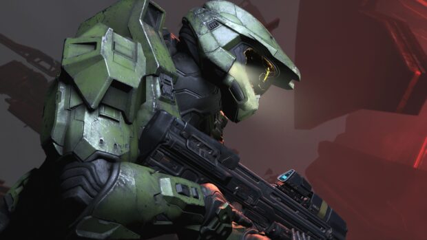 Master Chief in green armor holding a futuristic weapon in a dark environment
