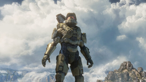 Master Chief stands ready in armor with a cloudy sky and rocky landscape in the background