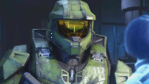 Master Chief in green armor standing inside a dimly lit room with a yellow visor