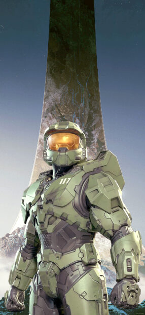 Master Chief in green armor standing in front of a large ring structure on an alien planet