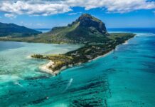 A scenic view of Mauritius Island showcasing clear turquoise waters and a prominent mountain in the background
