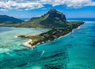 A scenic view of Mauritius Island showcasing clear turquoise waters and a prominent mountain in the background