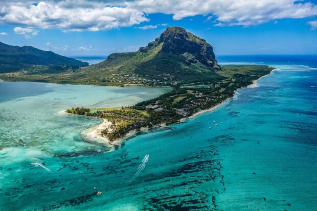 A scenic view of Mauritius Island showcasing clear turquoise waters and a prominent mountain in the background
