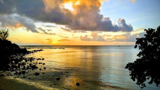 Quiet coastline of Mauritius Island during sunset with scattered clouds and calm sea water