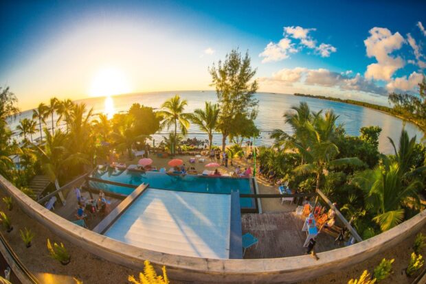 A vibrant Mauritius Island sunset view over tropical trees and a pool with people enjoying the scene